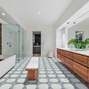 Long bathroom with decorative tile on the floor and wooden amenities